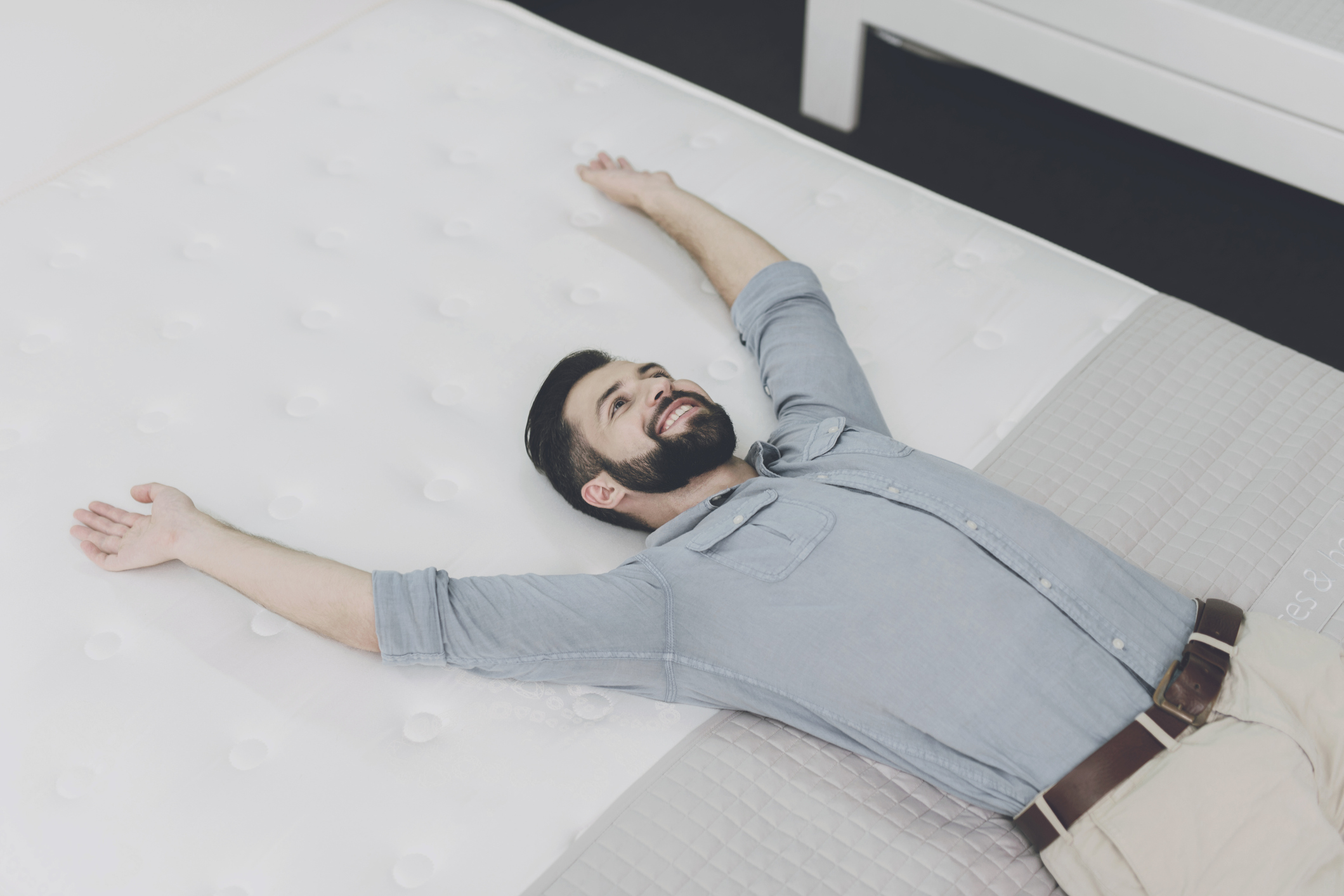 A smiling man sprawling on a mattress